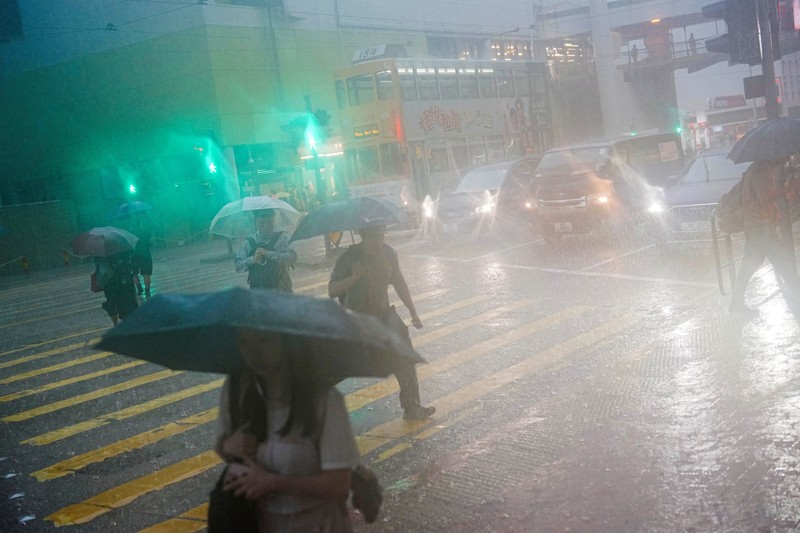 Banjir saat hujan deras di Hong Kong, Selasa (5/8/2025). Pejalan kaki berjalan melewati area yang terendam banjir saat hujan deras di Hong Kong, Selasa (5/8/2025). (REUTERS/Lam Yik)