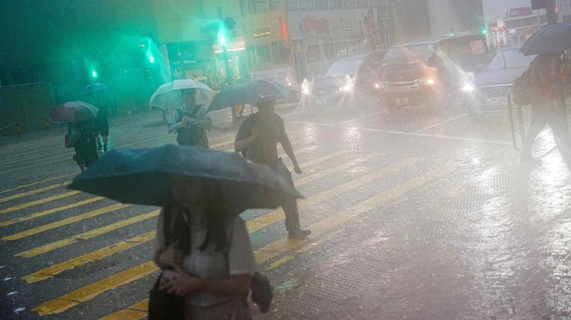 Pejalan kaki berjalan melewati area yang terendam banjir saat hujan deras di Hong Kong, Selasa (5/8/2025). (REUTERS/Lam Yik)