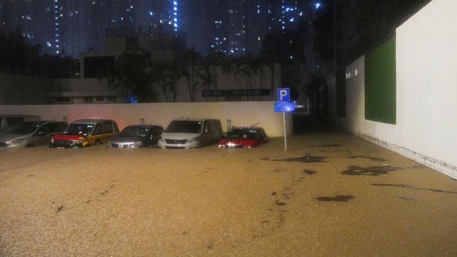Pejalan kaki berjalan melewati area yang terendam banjir saat hujan deras di Hong Kong, Selasa (5/8/2025). (REUTERS/Lam Yik)