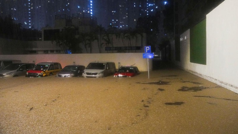Pejalan kaki berjalan melewati area yang terendam banjir saat hujan deras di Hong Kong, Selasa (5/8/2025). (REUTERS/Lam Yik)