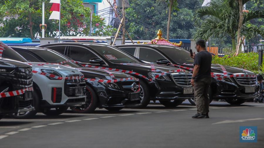 Petugas melihat mobil sitaan milik raja minyak Riza Chalid yang terparkir di Gedung Jampidsus, Kejaksaan Agung (Kejagung), Jakarta, Selasa (5/8/2025). (CNBC Indonesia/Faisal Rahman)