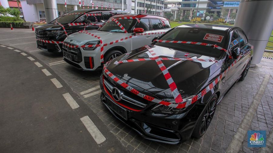Petugas melihat mobil sitaan milik raja minyak Riza Chalid yang terparkir di Gedung Jampidsus, Kejaksaan Agung (Kejagung), Jakarta, Selasa (5/8/2025). (CNBC Indonesia/Faisal Rahman)