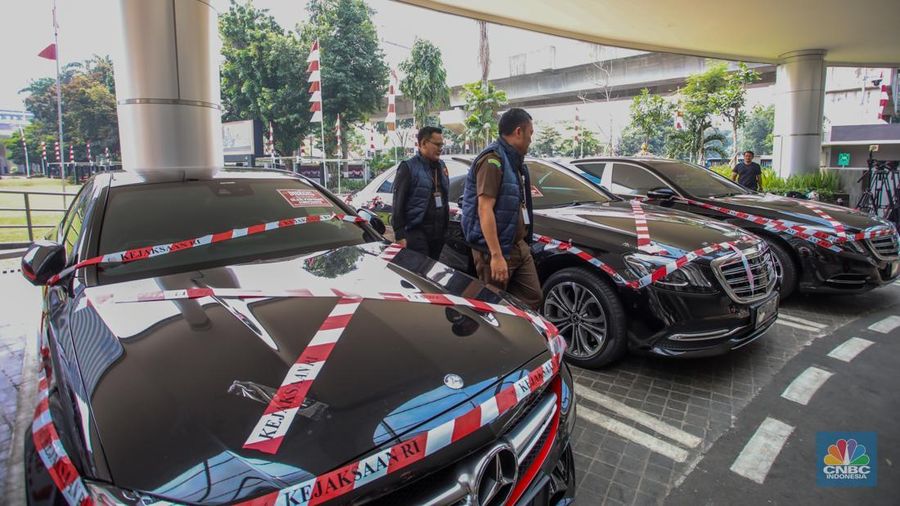 Petugas melihat mobil sitaan milik raja minyak Riza Chalid yang terparkir di Gedung Jampidsus, Kejaksaan Agung (Kejagung), Jakarta, Selasa (5/8/2025). (CNBC Indonesia/Faisal Rahman)