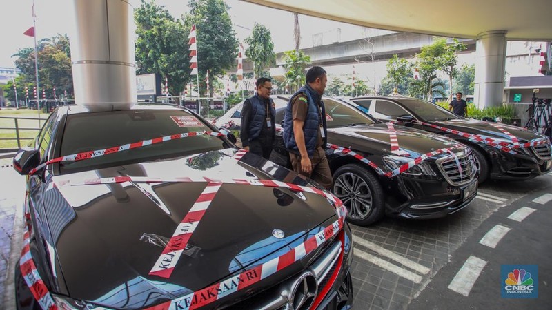 Petugas melihat mobil sitaan milik raja minyak Riza Chalid yang terparkir di Gedung Jampidsus, Kejaksaan Agung (Kejagung), Jakarta, Selasa (5/8/2025). (CNBC Indonesia/Faisal Rahman)