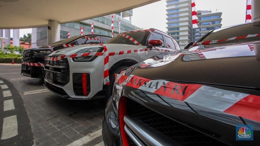 Petugas melihat mobil sitaan milik raja minyak Riza Chalid yang terparkir di Gedung Jampidsus, Kejaksaan Agung (Kejagung), Jakarta, Selasa (5/8/2025). (CNBC Indonesia/Faisal Rahman)