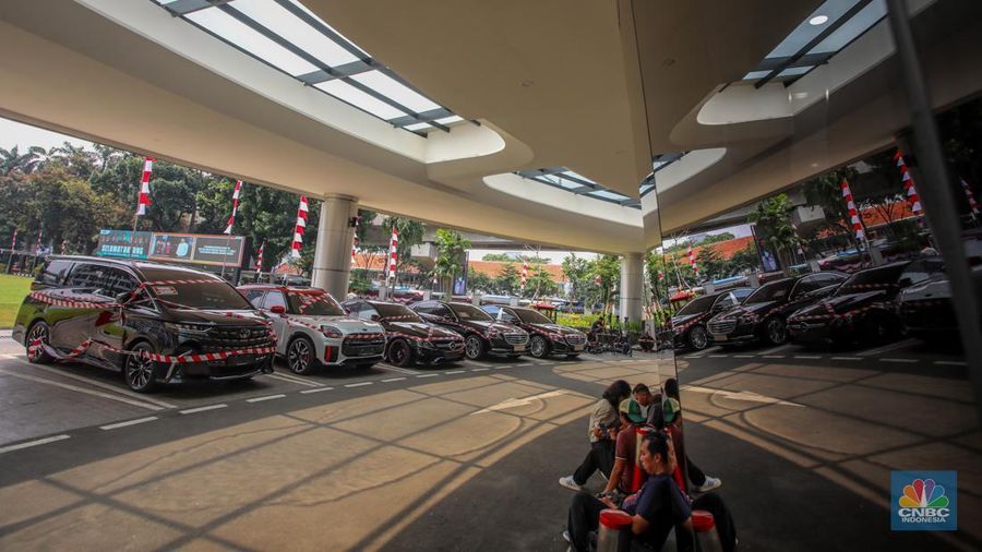 Petugas melihat mobil sitaan milik raja minyak Riza Chalid yang terparkir di Gedung Jampidsus, Kejaksaan Agung (Kejagung), Jakarta, Selasa (5/8/2025). (CNBC Indonesia/Faisal Rahman)