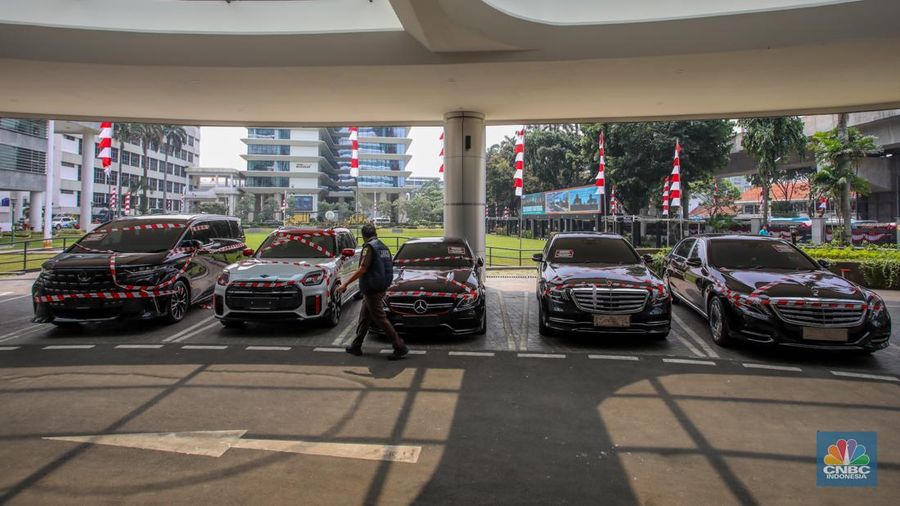 Petugas melihat mobil sitaan milik raja minyak Riza Chalid yang terparkir di Gedung Jampidsus, Kejaksaan Agung (Kejagung), Jakarta, Selasa (5/8/2025). (CNBC Indonesia/Faisal Rahman)