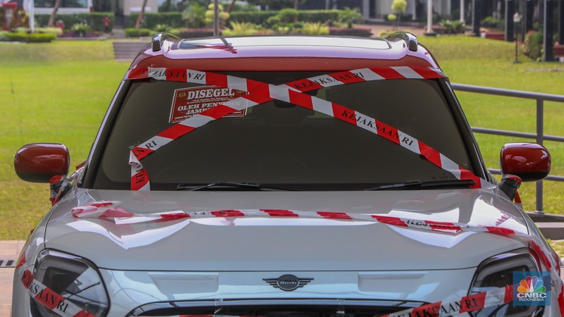 Petugas melihat mobil sitaan milik raja minyak Riza Chalid yang terparkir di Gedung Jampidsus, Kejaksaan Agung (Kejagung), Jakarta. Petugas melihat mobil sitaan milik raja minyak Riza Chalid yang terparkir di Gedung Jampidsus, Kejaksaan Agung (Kejagung), Jakarta, Selasa (5/8/2025). (CNBC Indonesia/Faisal Rahman)