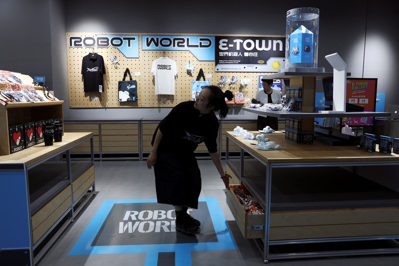 CHINA-ROBOTS/ A staff member works at a section selling Robot World merchandise, during an organised media tour to Robot Mall, a store selling humanoid and other robots, in Beijing, China August 6, 2025. REUTERS/Florence Lo