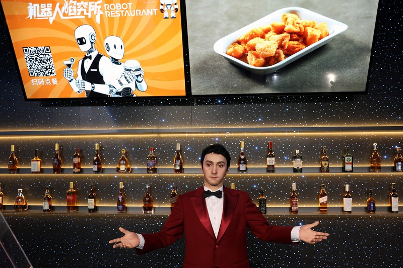 CHINA-ROBOTS/ A staff member works at a section selling Robot World merchandise, during an organised media tour to Robot Mall, a store selling humanoid and other robots, in Beijing, China August 6, 2025. REUTERS/Florence Lo