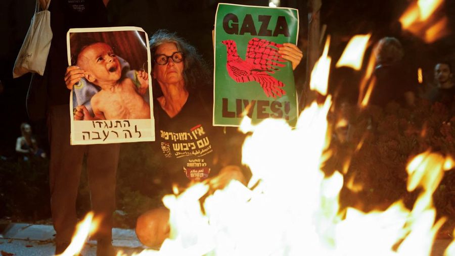 Demonstrators and relatives of hostages kidnapped during the deadly October 7, 2023, attack on Israel by Hamas, protest demanding the immediate release of the hostages and the end of the war, as a fire burns in Tel Aviv, Israel, August 7, 2025. REUTERS/Ammar Awad