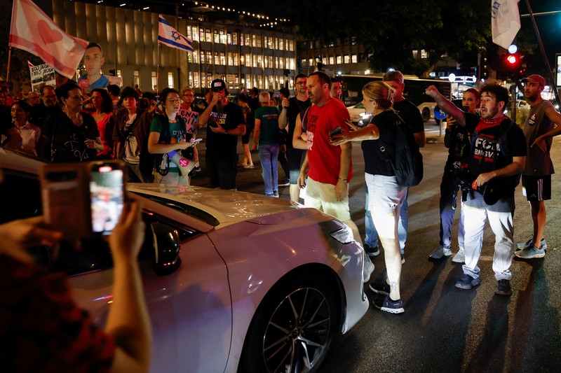 Demonstrators and relatives of hostages kidnapped during the deadly October 7, 2023, attack on Israel by Hamas, protest demanding the immediate release of the hostages and the end of the war, as a fire burns in Tel Aviv, Israel, August 7, 2025. REUTERS/Ammar Awad