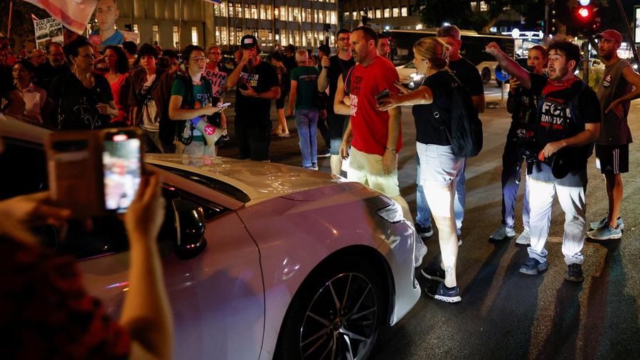 Demonstrators and relatives of hostages kidnapped during the deadly October 7, 2023, attack on Israel by Hamas, protest demanding the immediate release of the hostages and the end of the war, as a fire burns in Tel Aviv, Israel, August 7, 2025. REUTERS/Ammar Awad