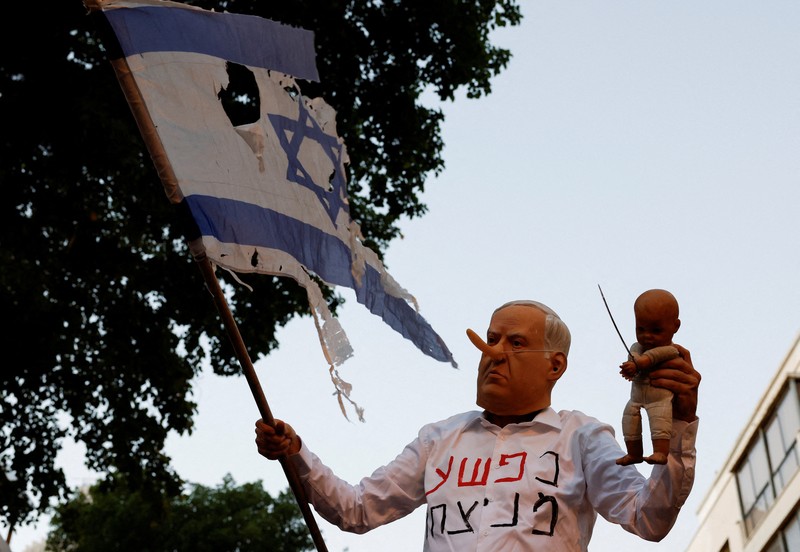 Demonstrators and relatives of hostages kidnapped during the deadly October 7, 2023, attack on Israel by Hamas, protest demanding the immediate release of the hostages and the end of the war, as a fire burns in Tel Aviv, Israel, August 7, 2025. REUTERS/Ammar Awad