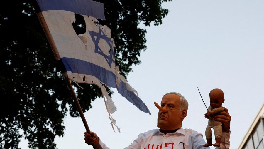Demonstrators and relatives of hostages kidnapped during the deadly October 7, 2023, attack on Israel by Hamas, protest demanding the immediate release of the hostages and the end of the war, as a fire burns in Tel Aviv, Israel, August 7, 2025. REUTERS/Ammar Awad
