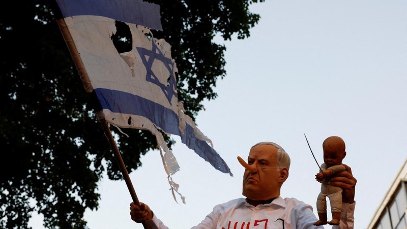 Demonstrators and relatives of hostages kidnapped during the deadly October 7, 2023, attack on Israel by Hamas, protest demanding the immediate release of the hostages and the end of the war, as a fire burns in Tel Aviv, Israel, August 7, 2025. REUTERS/Ammar Awad
