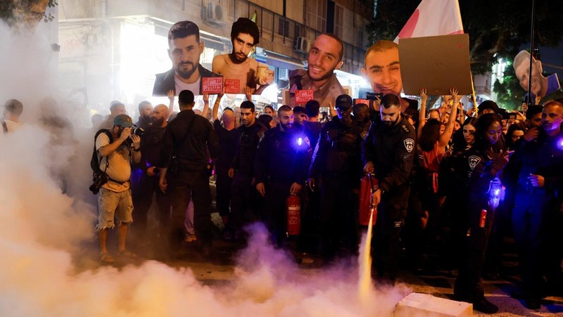 Demonstrators and relatives of hostages kidnapped during the deadly October 7, 2023, attack on Israel by Hamas, protest demanding the immediate release of the hostages and the end of the war, as a fire burns in Tel Aviv, Israel, August 7, 2025. REUTERS/Ammar Awad