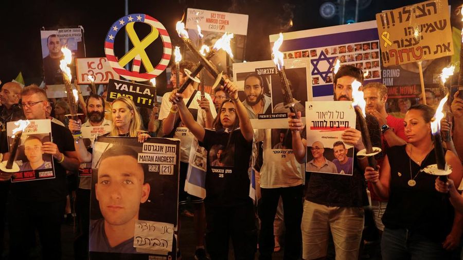 Demonstrators and relatives of hostages kidnapped during the deadly October 7, 2023, attack on Israel by Hamas, protest demanding the immediate release of the hostages and the end of the war, as a fire burns in Tel Aviv, Israel, August 7, 2025. REUTERS/Ammar Awad