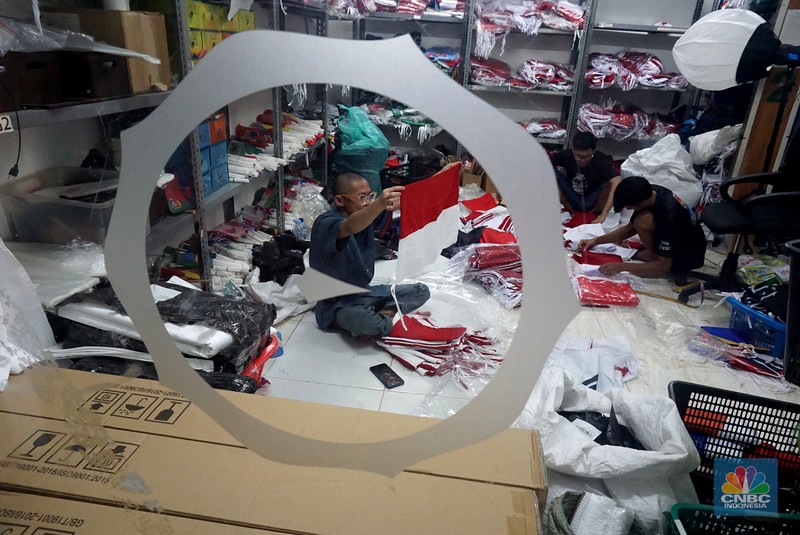 Pekerja melipat bendera di usaha konveksi rumahan yang memproduksi bendera umbul-umbul merah putih, topi, hingga kaos di kawasan Tangerang Selatan, Banten, Senin (11/8/2025). (CNBC Indonesia/Muhammad Sabki)