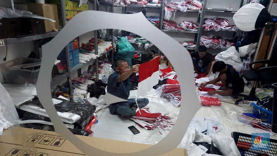 Pekerja melipat bendera di usaha konveksi rumahan yang memproduksi bendera umbul-umbul merah putih, topi, hingga kaos di kawasan Tangerang Selatan, Banten, Senin (11/8/2025). (CNBC Indonesia/Muhammad Sabki)