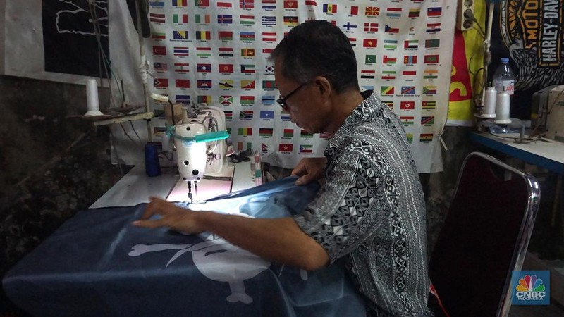 Pekerja melipat bendera di usaha konveksi rumahan yang memproduksi bendera umbul-umbul merah putih, topi, hingga kaos di kawasan Tangerang Selatan, Banten, Senin (11/8/2025). (CNBC Indonesia/Muhammad Sabki)