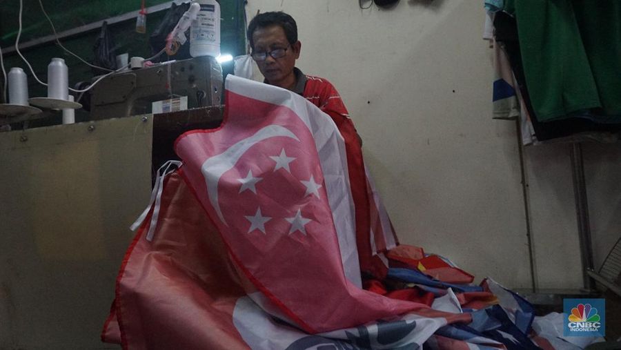 Pekerja melipat bendera di usaha konveksi rumahan yang memproduksi bendera umbul-umbul merah putih, topi, hingga kaos di kawasan Tangerang Selatan, Banten, Senin (11/8/2025). (CNBC Indonesia/Muhammad Sabki)