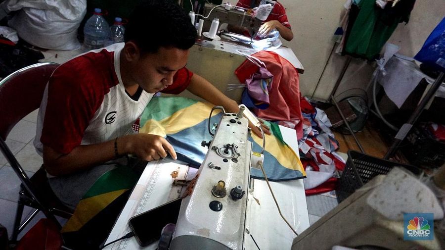 Pekerja melipat bendera di usaha konveksi rumahan yang memproduksi bendera umbul-umbul merah putih, topi, hingga kaos di kawasan Tangerang Selatan, Banten, Senin (11/8/2025). (CNBC Indonesia/Muhammad Sabki)