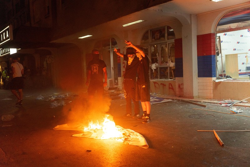 Orang-orang bereaksi di samping ledakan kembang api, selama kebuntuan antara pendukung partai yang berkuasa dan pengunjuk rasa anti-pemerintah di Beograd, Serbia, 14 Agustus 2025. (REUTERS/Djordje Kojadinovic)