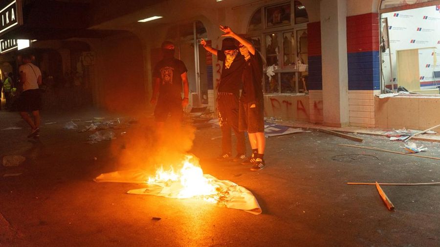 Orang-orang bereaksi di samping ledakan kembang api, selama kebuntuan antara pendukung partai yang berkuasa dan pengunjuk rasa anti-pemerintah di Beograd, Serbia, 14 Agustus 2025. (REUTERS/Djordje Kojadinovic)