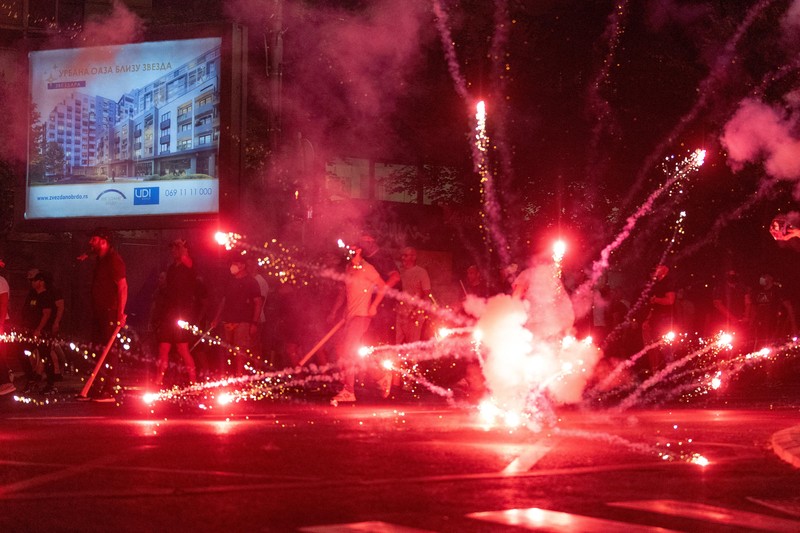Orang-orang bereaksi di samping ledakan kembang api, selama kebuntuan antara pendukung partai yang berkuasa dan pengunjuk rasa anti-pemerintah di Beograd, Serbia, 14 Agustus 2025. (REUTERS/Djordje Kojadinovic)