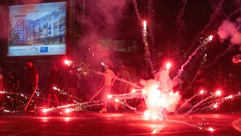 Orang-orang bereaksi di samping ledakan kembang api, selama kebuntuan antara pendukung partai yang berkuasa dan pengunjuk rasa anti-pemerintah di Beograd, Serbia, 14 Agustus 2025. (REUTERS/Djordje Kojadinovic)
