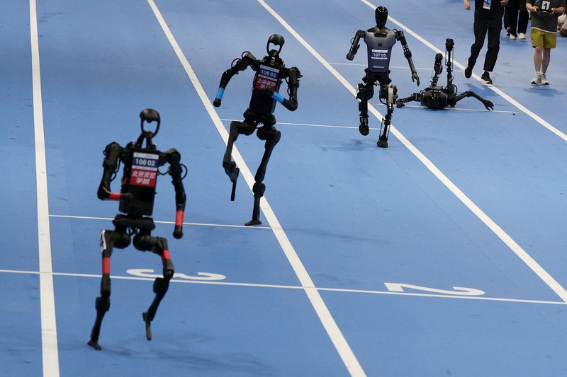 Unitree Robotics and Tiangong humanoid robots compete in the 100m final at the inaugural World Humanoid Robot Games, at the National Speed Skating Oval in Beijing, China August 17, 2025.  REUTERS/Florence Lo     TPX IMAGES OF THE DAY