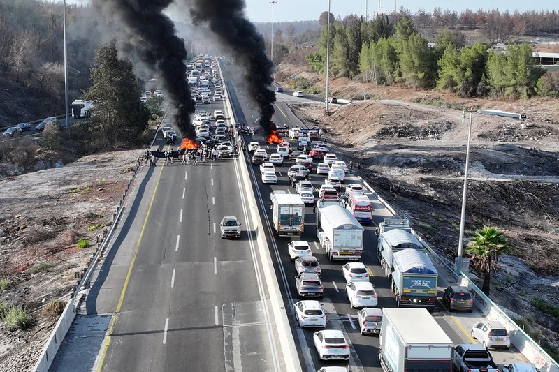Foto drone menunjukkan para pengunjuk rasa berdiri di samping ban yang terbakar saat mereka memblokir jalan raya utama Israel yang menghubungkan Yerusalem dan Tel Aviv dekat Latrun, Israel, setelah keluarga sandera menyerukan pemogokan nasional untuk menuntut pengembalian semua sandera dan diakhirinya perang di Gaza, 17 Agustus 2025. Foto drone menunjukkan para pengunjuk rasa berdiri di samping ban yang terbakar saat mereka memblokir jalan raya utama Israel yang menghubungkan Yerusalem dan Tel Aviv dekat Latrun, Israel, setelah keluarga sandera menyerukan pemogokan nasional untuk menuntut pengembalian semua sandera dan diakhirinya perang di Gaza, 17 Agustus 2025. (REUTERS/Stringer)