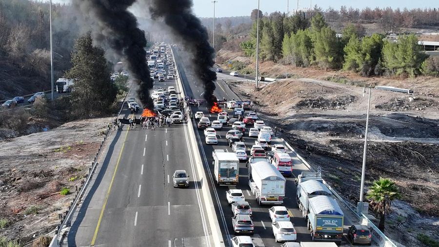 Foto drone menunjukkan para pengunjuk rasa berdiri di samping ban yang terbakar saat mereka memblokir jalan raya utama Israel yang menghubungkan Yerusalem dan Tel Aviv dekat Latrun, Israel, setelah keluarga sandera menyerukan pemogokan nasional untuk menuntut pengembalian semua sandera dan diakhirinya perang di Gaza, 17 Agustus 2025. (REUTERS/Stringer)