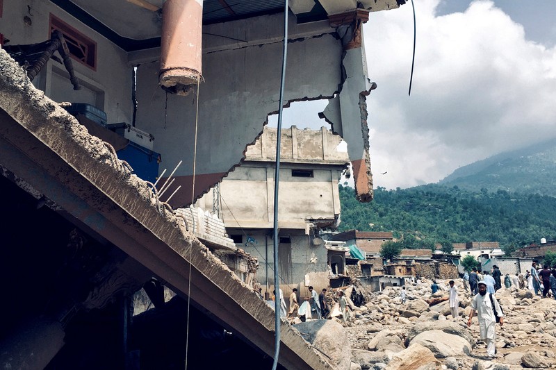 Seorang pria duduk di samping rumah-rumah yang rusak akibat hujan lebat dan banjir di distrik Buner di provinsi Khyber Pakhtunkhwa, Pakistan, 16 Agustus 2025. (REUTERS/Stringer)
