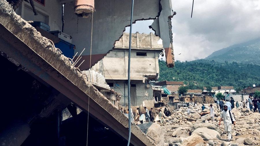 Seorang pria duduk di samping rumah-rumah yang rusak akibat hujan lebat dan banjir di distrik Buner di provinsi Khyber Pakhtunkhwa, Pakistan, 16 Agustus 2025. (REUTERS/Stringer)