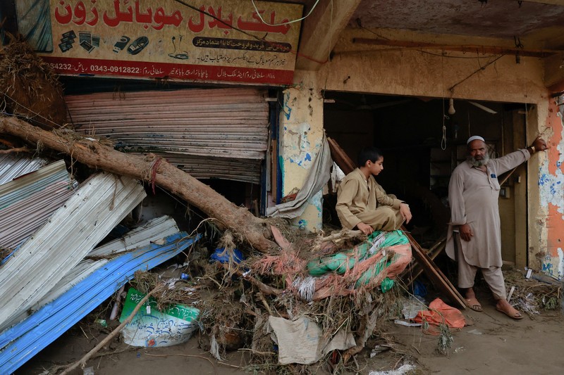 Seorang pria duduk di samping rumah-rumah yang rusak akibat hujan lebat dan banjir di distrik Buner di provinsi Khyber Pakhtunkhwa, Pakistan, 16 Agustus 2025. (REUTERS/Stringer)