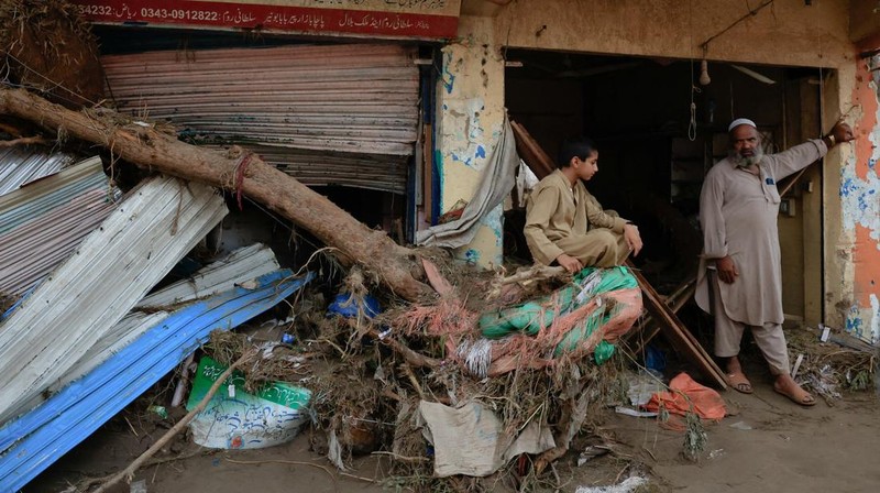 Seorang pria duduk di samping rumah-rumah yang rusak akibat hujan lebat dan banjir di distrik Buner di provinsi Khyber Pakhtunkhwa, Pakistan, 16 Agustus 2025. (REUTERS/Stringer)