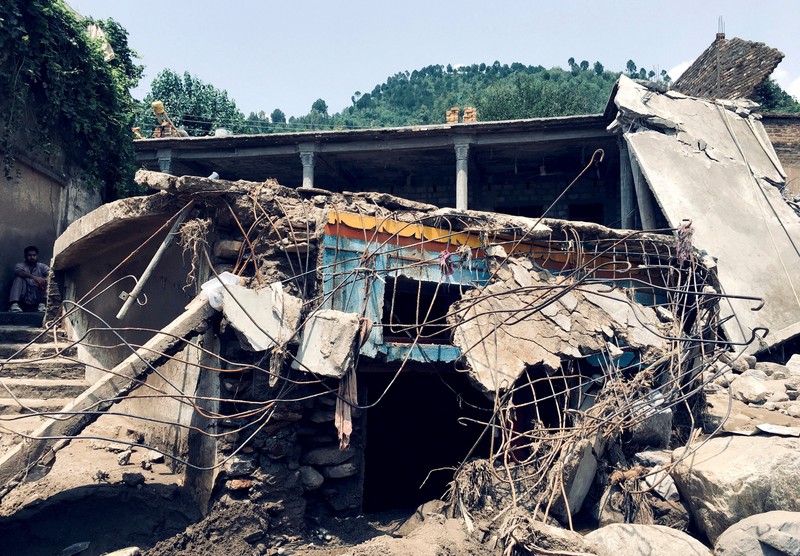 Seorang pria duduk di samping rumah-rumah yang rusak akibat hujan lebat dan banjir di distrik Buner di provinsi Khyber Pakhtunkhwa, Pakistan, 16 Agustus 2025. (REUTERS/Stringer)