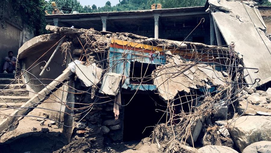 Seorang pria duduk di samping rumah-rumah yang rusak akibat hujan lebat dan banjir di distrik Buner di provinsi Khyber Pakhtunkhwa, Pakistan, 16 Agustus 2025. (REUTERS/Stringer)