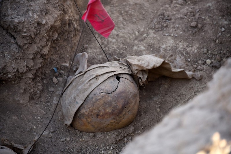 Tengkorak manusia ditandai dengan pita merah di situs Khasfa dekat kota Mosul di Irak utara, tempat pihak berwenang mulai menggali kuburan massal yang diyakini berisi ribuan korban ISIS, Minggu (17/8/2025). (AFP/ZAID AL-OBEIDI)