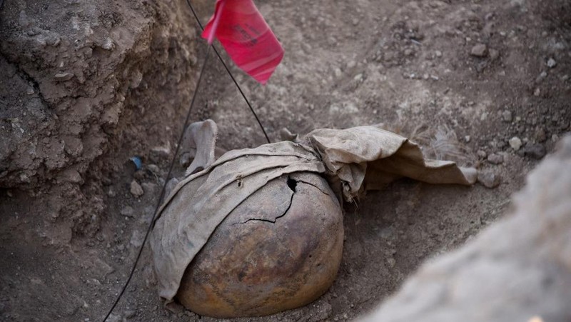 Tengkorak manusia ditandai dengan pita merah di situs Khasfa dekat kota Mosul di Irak utara, tempat pihak berwenang mulai menggali kuburan massal yang diyakini berisi ribuan korban ISIS, Minggu (17/8/2025). (AFP/ZAID AL-OBEIDI)