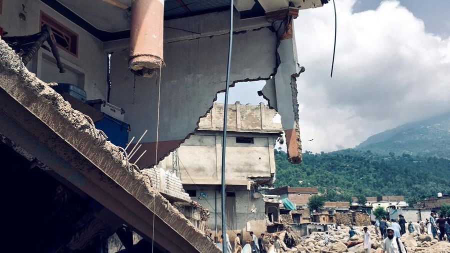 Warga duduk di antara puing-puing rumah yang rusak akibat badai yang menyebabkan hujan lebat dan banjir, di Bayshonai Kalay, distrik Buner, provinsi Khyber Pakhtunkhwa, Pakistan. Warga duduk di antara puing-puing rumah yang rusak akibat badai yang menyebabkan hujan lebat dan banjir, di Bayshonai Kalay, distrik Buner, provinsi Khyber Pakhtunkhwa, Pakistan, 17 Agustus 2025. (REUTERS/Akhtar Soomro)