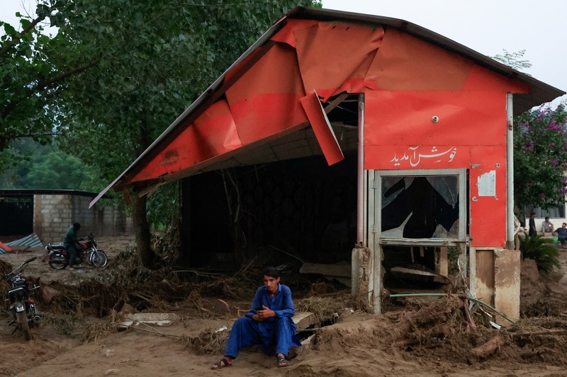 Warga duduk di antara puing-puing rumah yang rusak akibat badai yang menyebabkan hujan lebat dan banjir, di Bayshonai Kalay, distrik Buner, provinsi Khyber Pakhtunkhwa, Pakistan, 17 Agustus 2025. (REUTERS/Akhtar Soomro)