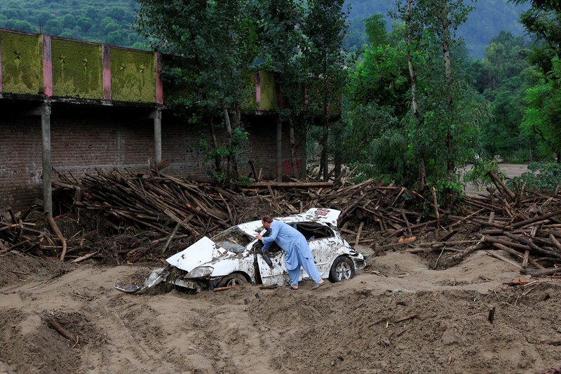 Warga duduk di antara puing-puing rumah yang rusak akibat badai yang menyebabkan hujan lebat dan banjir, di Bayshonai Kalay, distrik Buner, provinsi Khyber Pakhtunkhwa, Pakistan, 17 Agustus 2025. (REUTERS/Akhtar Soomro)