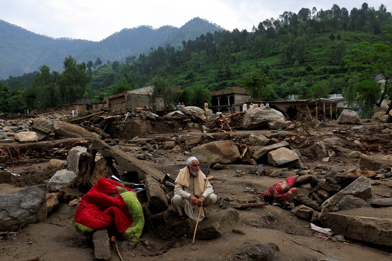 Warga duduk di antara puing-puing rumah yang rusak akibat badai yang menyebabkan hujan lebat dan banjir, di Bayshonai Kalay, distrik Buner, provinsi Khyber Pakhtunkhwa, Pakistan. Warga duduk di antara puing-puing rumah yang rusak akibat badai yang menyebabkan hujan lebat dan banjir, di Bayshonai Kalay, distrik Buner, provinsi Khyber Pakhtunkhwa, Pakistan, 17 Agustus 2025. (REUTERS/Akhtar Soomro)
