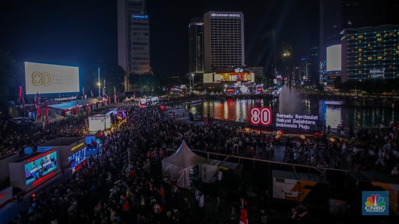 Warga menyaksikan iring-iringan karnaval saat melintas di kawasan Bundaran HI, Jakarta, Minggu (17/8/2025) malam. Acara karnaval ini menjadi pertama kalinya digelar pihak Istana dalam peringatan HUT RI. (CNBC Indonesia/Faisal Rahman)