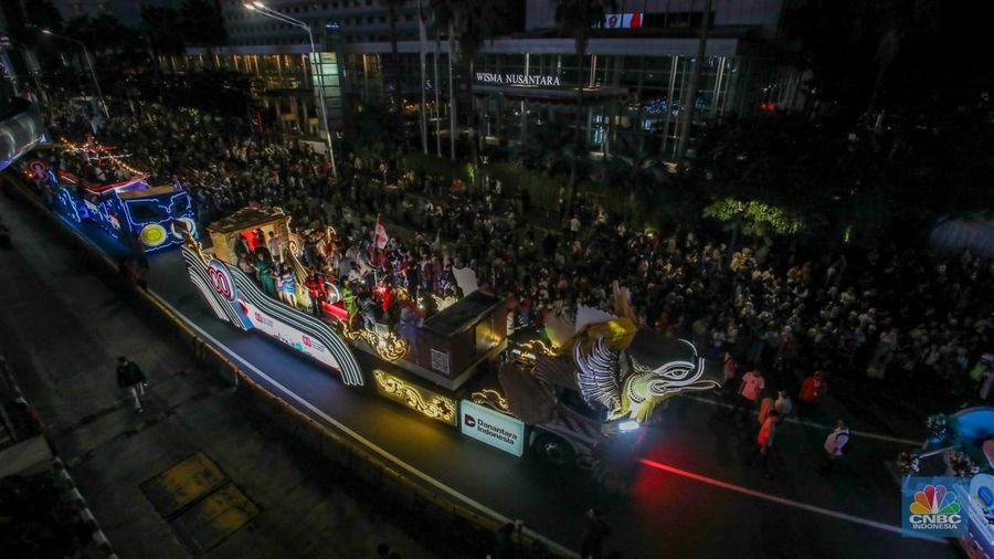 Warga menyaksikan iring-iringan karnaval saat melintas di kawasan Bundaran HI, Jakarta, Minggu (17/8/2025) malam. Acara karnaval ini menjadi pertama kalinya digelar pihak Istana dalam peringatan HUT RI. (CNBC Indonesia/Faisal Rahman)