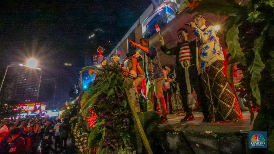 Warga menyaksikan iring-iringan karnaval saat melintas di kawasan Bundaran HI, Jakarta, Minggu (17/8/2025) malam. Acara karnaval ini menjadi pertama kalinya digelar pihak Istana dalam peringatan HUT RI. (CNBC Indonesia/Faisal Rahman)
