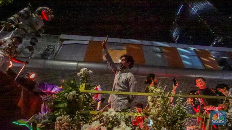Warga menyaksikan iring-iringan karnaval saat melintas di kawasan Bundaran HI, Jakarta, Minggu (17/8/2025) malam. Acara karnaval ini menjadi pertama kalinya digelar pihak Istana dalam peringatan HUT RI. (CNBC Indonesia/Faisal Rahman)